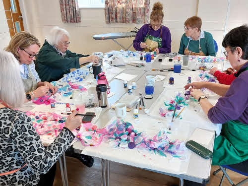 Six members engrossed in silk scarf painting